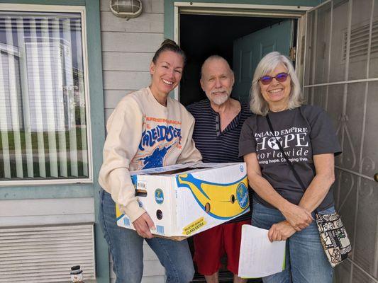 Friendly volunteers delivering a monthly family food box!  Compassion and community at the heart of every visit.