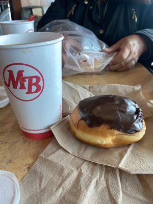 A medium coffe and a Boston cream donut