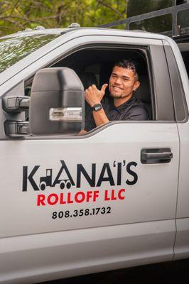 Our employee driving our white Kana'i's Junk Removal truck, smiling and giving the camera thumbs up.
