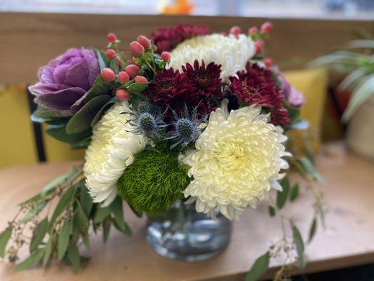 An arrangement made with kale, super mums, and eucalyptus