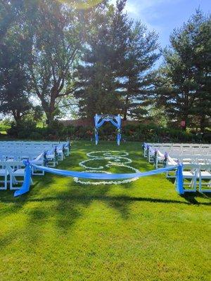 The wedding aisle for the ceremony. Flowers on the chair, petals on the ground and 3 arch pieces