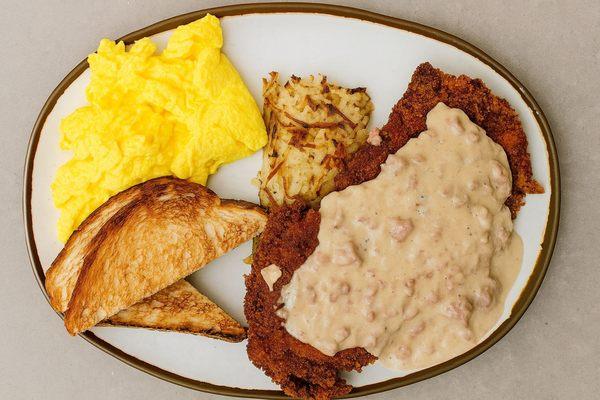 Chicken fried steak with scrambled eggs, hashbrowns, and buttered sourdough toast.