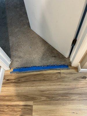 Left doorway carpet untrimmed and untucked -should have been folded under transition strip. Left 3 doorways like this.