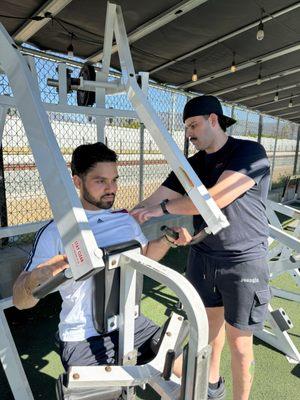 personal trainer Carlos adjusting form during row.