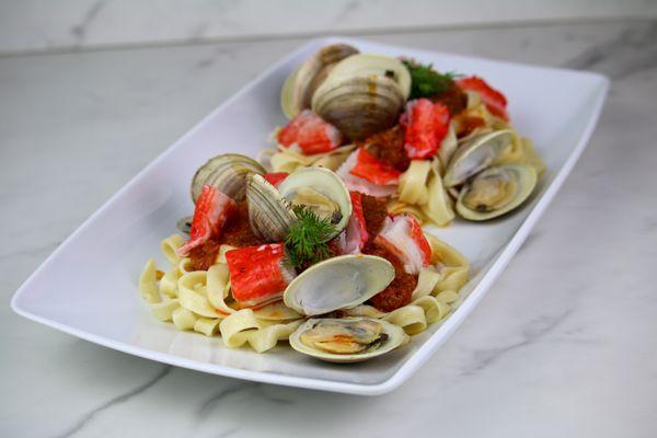 King Crab and Clam Tagliatelle: Delicate tagliatelle pasta is served with succulent king crab and a mix of clams, tossed in a pomodoro sauce