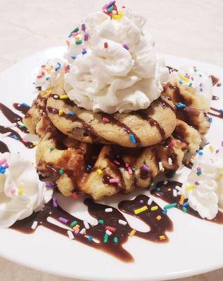 Signature Liege Waffle topped with a fresh-baked chocolate chip cookie, chocolate syrup, whipped cream, and sprinkles.