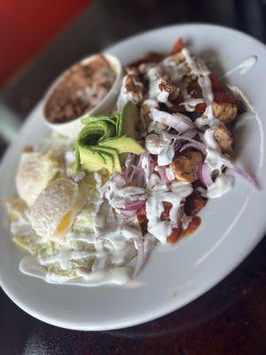 Famous chilaquiles (green with fried egg & red with chicken) served with beans and ordered with avocado