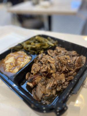 Smothered pork chop with mashed potatoes and collard greens