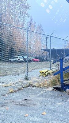 Car stuck in impound. Only vehicle that is recent. Otherwise empty lot, and sketchy fenced in yard with run down building.