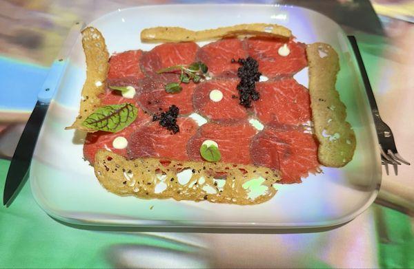 Banksy Veal carpaccio wrapped in herbs and lime, truffle mayonnaise, olive soil, Sakura cress & toasted olive bread