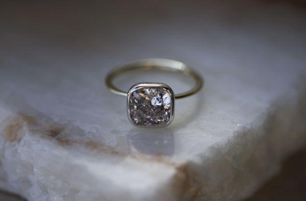 Cushion cut diamond engagement ring set in 18k yellow gold and platinum.