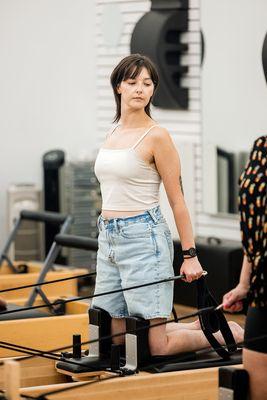 A person mid-movement on a Pilates Reformer