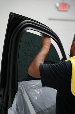 Technician carefully applying tint on window while maintaining the car clean.