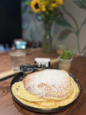 Plate size pancakes with a side of blueberries.