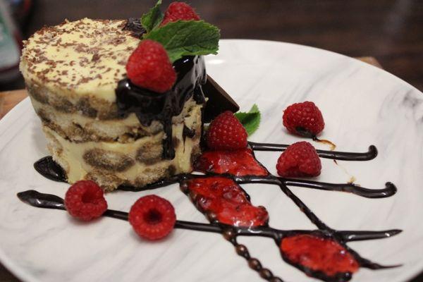 Tirimisu with drizzled chocolate syrup with raspberries.