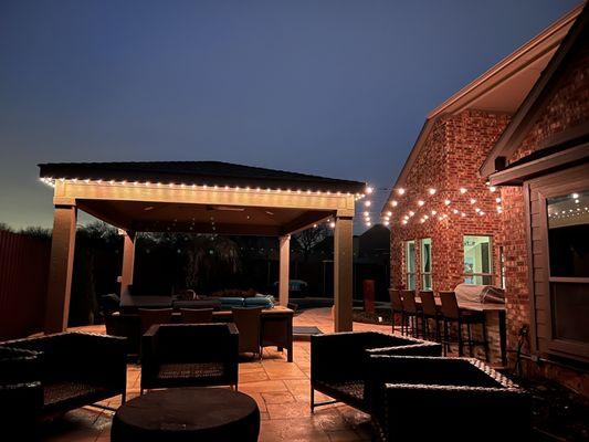 Patio cover wrapped with bistro lights strung to the house