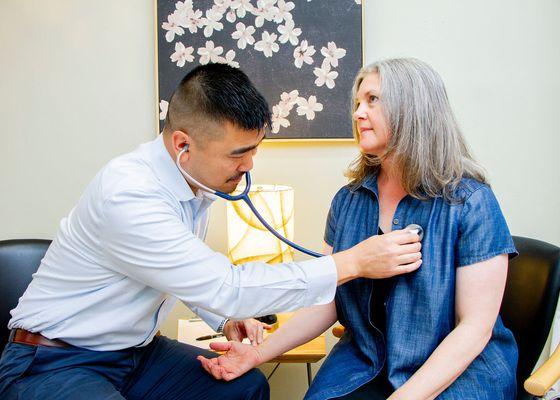 Dr. Andrew checking pulse and using a stethoscope to listen to heart sounds.