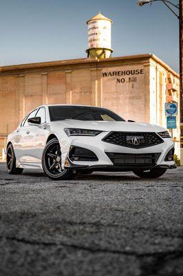 Jeff Wyler Acura of Dayton showcased in this photo, featuring a white Acura parked in front of a warehouse, highlighting slee...