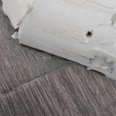 Poorly cut plank covered in putty. Cracked quarter round filled with caulk.