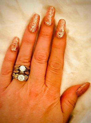 Full set of acrylic nails with pink sparkles mixed into the acrylic.