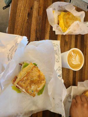 The Charlotte (Bacon Lettuce Tomato) on the biscuit of the day (Cheddar and Green Onion) with a vanilla latte