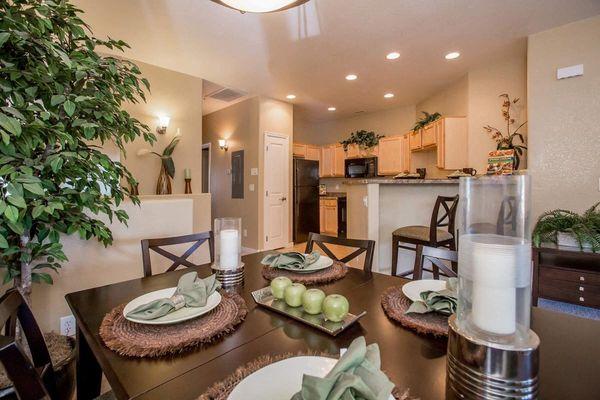 A dining table set with green apples and candles.