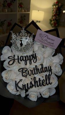 24 white roses with flutter, custom glitter topper, crown and black wrap.
