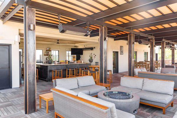 Comfortable shaded lounge seating beneath a stylish pergola, perfect for groups or solo guests to unwind with a drink in hand.