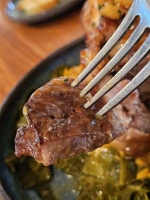 A fork holding a piece of The Slow Roasted Pork Shank.