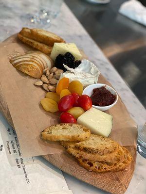 Cheese tasting board includes fruit, nuts, and preserves.