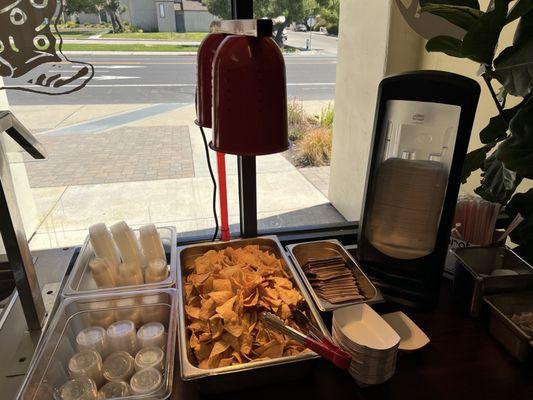Nachos and condiments portion cups to help yourself to. See also the condiment bar to its left side.