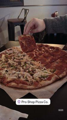 Half pepperoni and half chicken, jalapeño, mushroom and green pepper pizza.