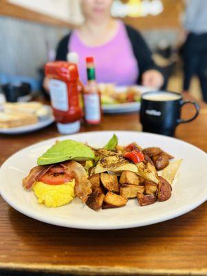 Bacon Avocado Omelette with a side of crispy potatoes with bell peppers and onions
