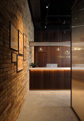 SSO's reception area blends warm exposed brick with modern wood finishes, creating a sophisticated yet welcoming first impression.
