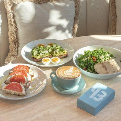 All day brunch table spread with tomato bagel, avocado smash
toast with soft-boiled eggs, kale caesar salad with chicken and
...