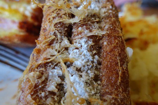 Powdered sugar laced edges with wisps of egg batter flowing.