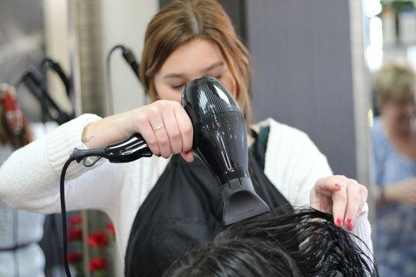 Hair Stylist, Maddie, drying a clients hair after applying hair color.