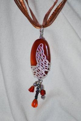 This handmade silver toned butterfly pendant is wrapped around a red agate.