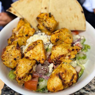 Greek Salad, two chicken skewer over it