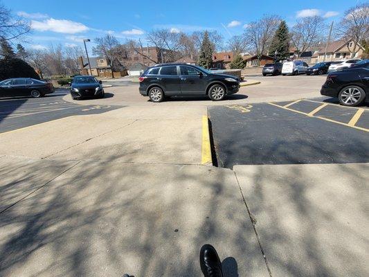 Two cars parked illegally in front of two of the three disability spaces and the incline to the sidewalk