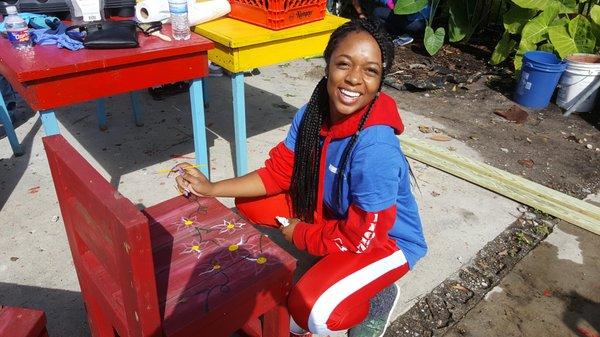 WWLTV Employee paints vibrant and colorful chairs at community garden.