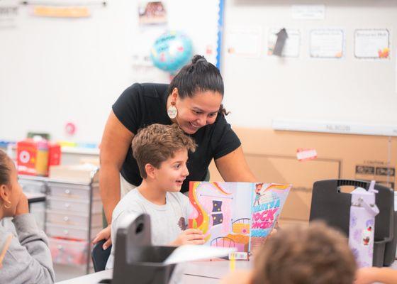 Teacher reading alongside an elementary student