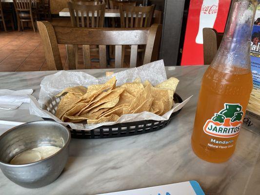 Chips and dip next to a mandarin Jarritos