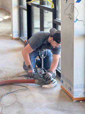 Crew member grinding concrete floor.