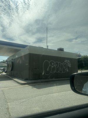 The back side of the gas station with some graffiti on it.