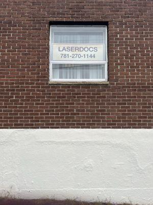 Sign in the side window of Laser Docs Cosmetic Laser Clinic. The entrance... is around the corner!