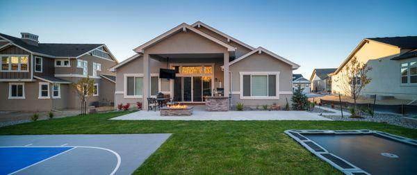 Landscape catered to an entertainers lifestyle. This yard features: a sport court, sunken trampoline, lawn area, fire pit, and outdoor TV.