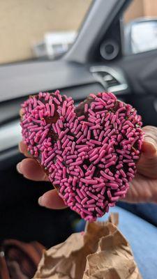 Heart shaped sugar doughnut with sprinkles.