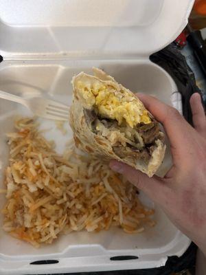 Breakfast burrito with egg, steak, hashbrowns, cheese, and onion, with hashbrowns on the side.