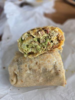 Three meat breakfast burrito with guacomole.